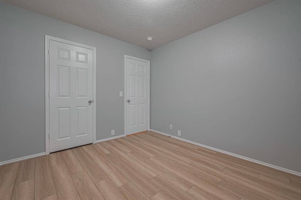This is another look from within the room with light wood flooring. It features 1 closet door and a simple ceiling light, offering a clean and neutral space ready for customization.