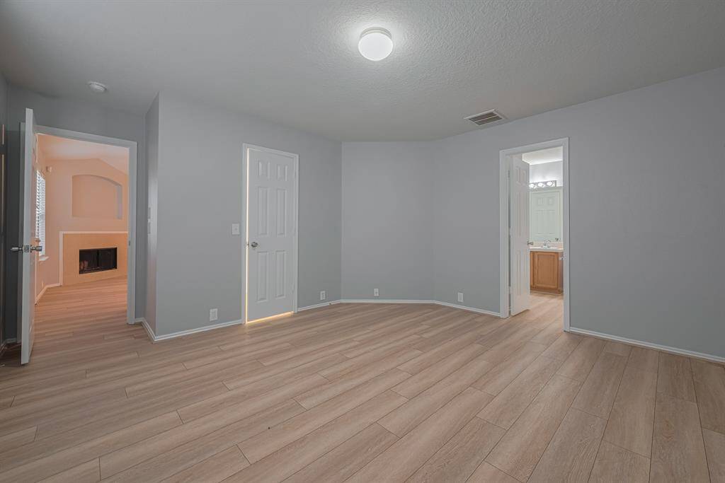 This room features light wood flooring and neutral walls, creating a bright, modern space. It connects to the primary bathroom and a living area with a fireplace, providing a cozy, functional layout.