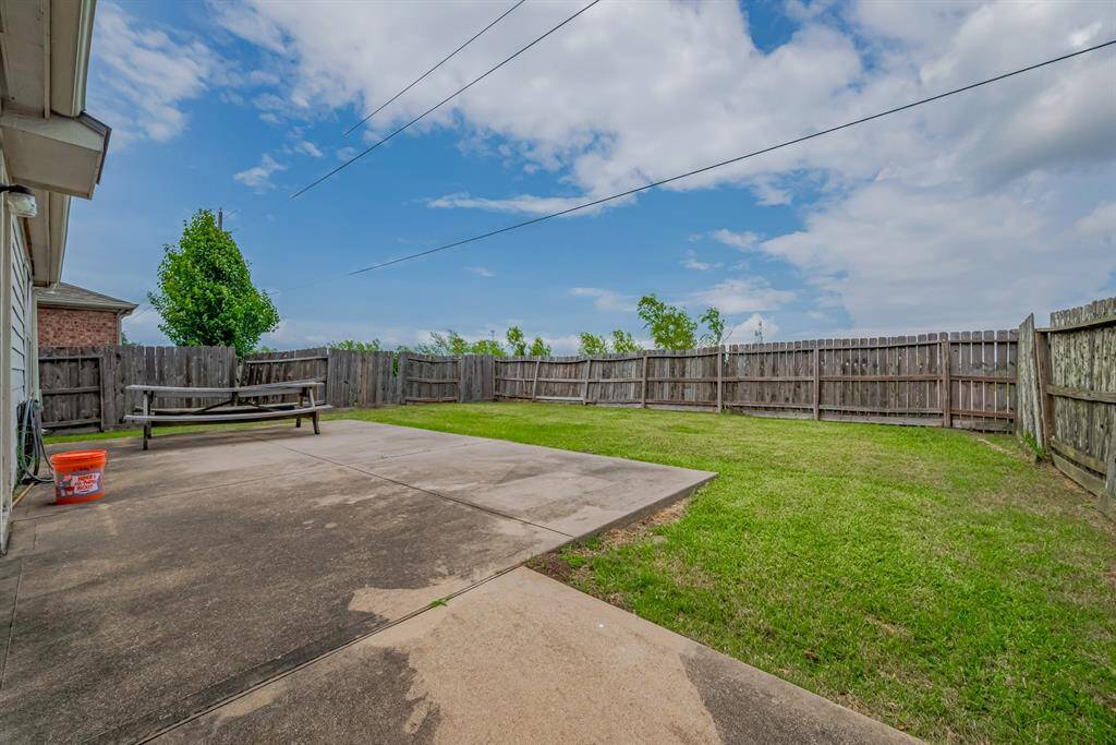 Spacious backyard with a concrete patio, grassy area, and wooden fencing. Perfect for outdoor activities and gatherings.