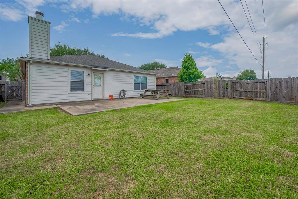 Spacious backyard with an expansive concrete patio, and a fenced perimeter for privacy. Ideal for outdoor activities and gatherings.