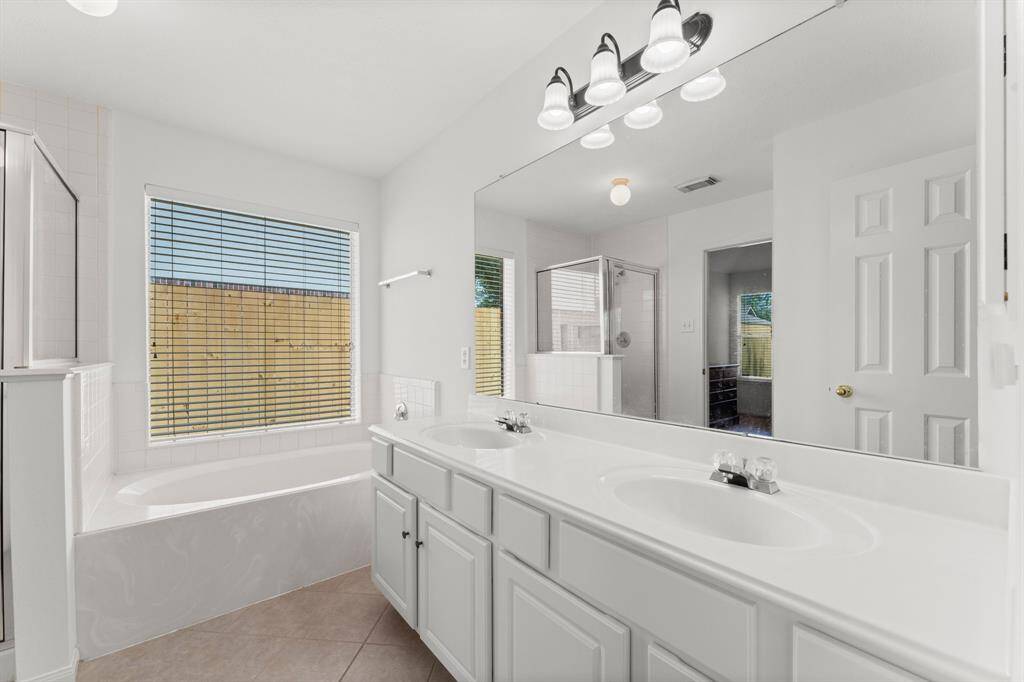 Gorgeous primary bathroom has great window, large garden soaking tub, double vanities offering generous counter space cabinet storage.