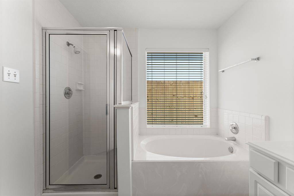 Walk-in shower has glass enclosure.