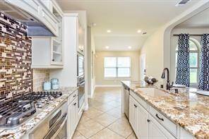 Different view of the island kitchen featuring double ovens and a gas cooktop.
