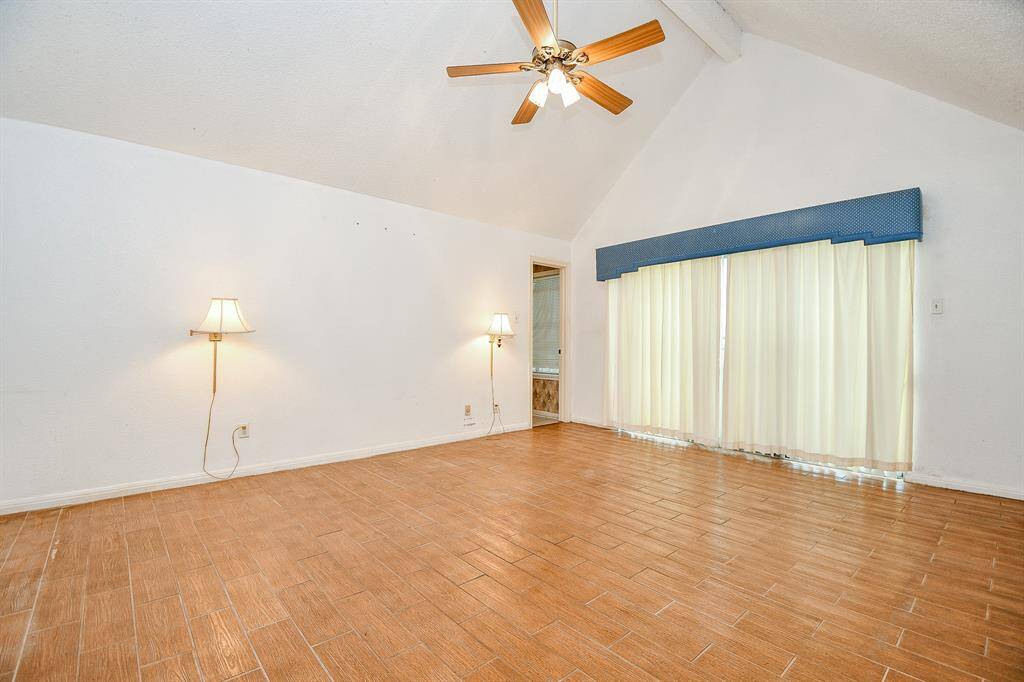 The primary suite has wood look tile for easy maintenance. Position your bed between the lamps and you have a great place to unwind at night with a book. Behind the curtains is another set of sliding glass doors.