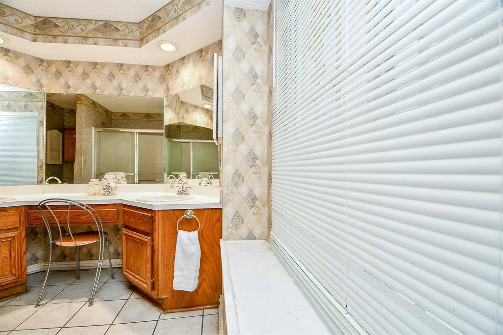 The primary ensuite has two sinks and a vanity area. The large window allows for natural light.