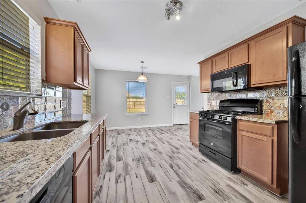 This stylish kitchen is fully equipped with granite countertops, ready-to-use appliances, and a gas stove.