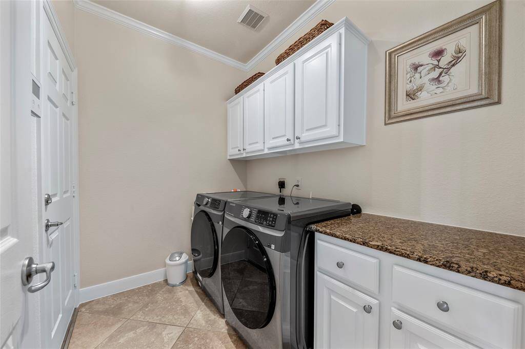 Functional laundry room equipped with modern appliances, ample cabinetry, and counter space for easy folding.