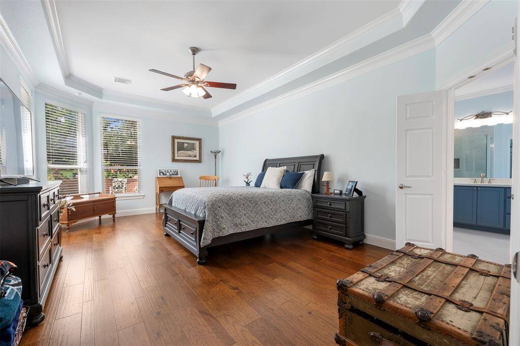 Primary bedroom with tray ceilings, oversized windows, and warm natural light creating a peaceful retreat