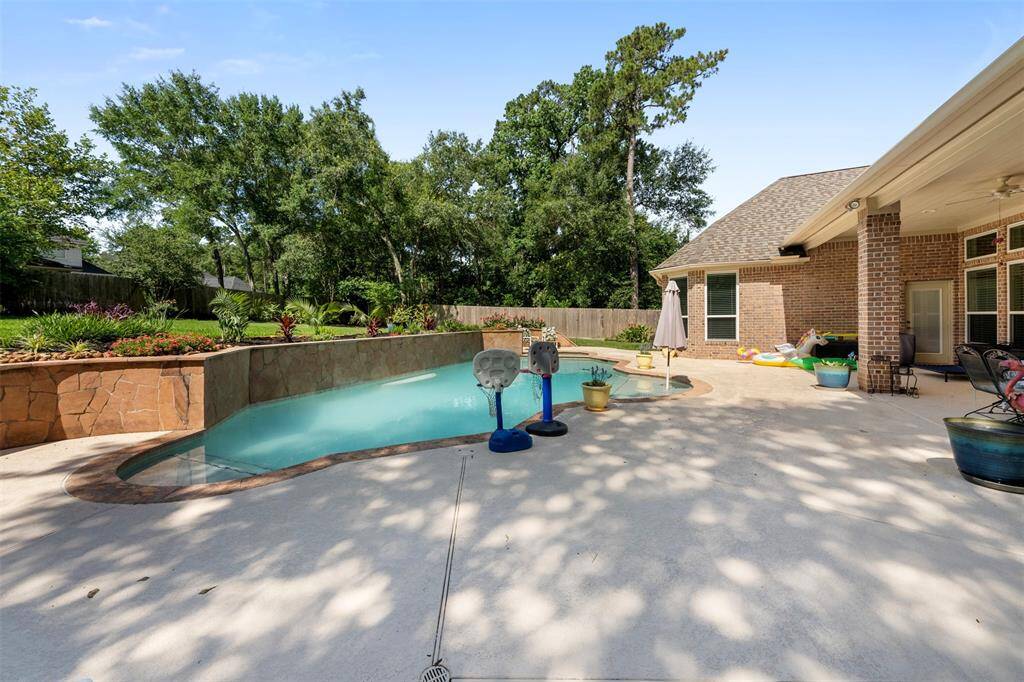 Expansive pool deck and vibrant landscaping frame the serene backyard retreat—ideal for entertaining