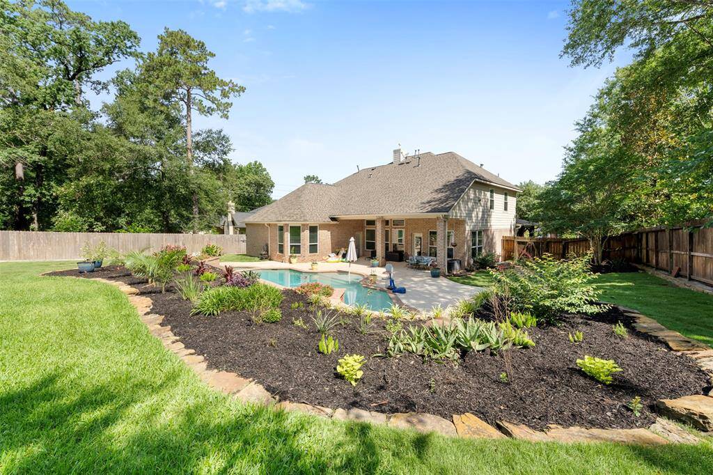 Backyard view showcases beautifully manicured flower beds surrounding the private pool—an entertainer’s dream