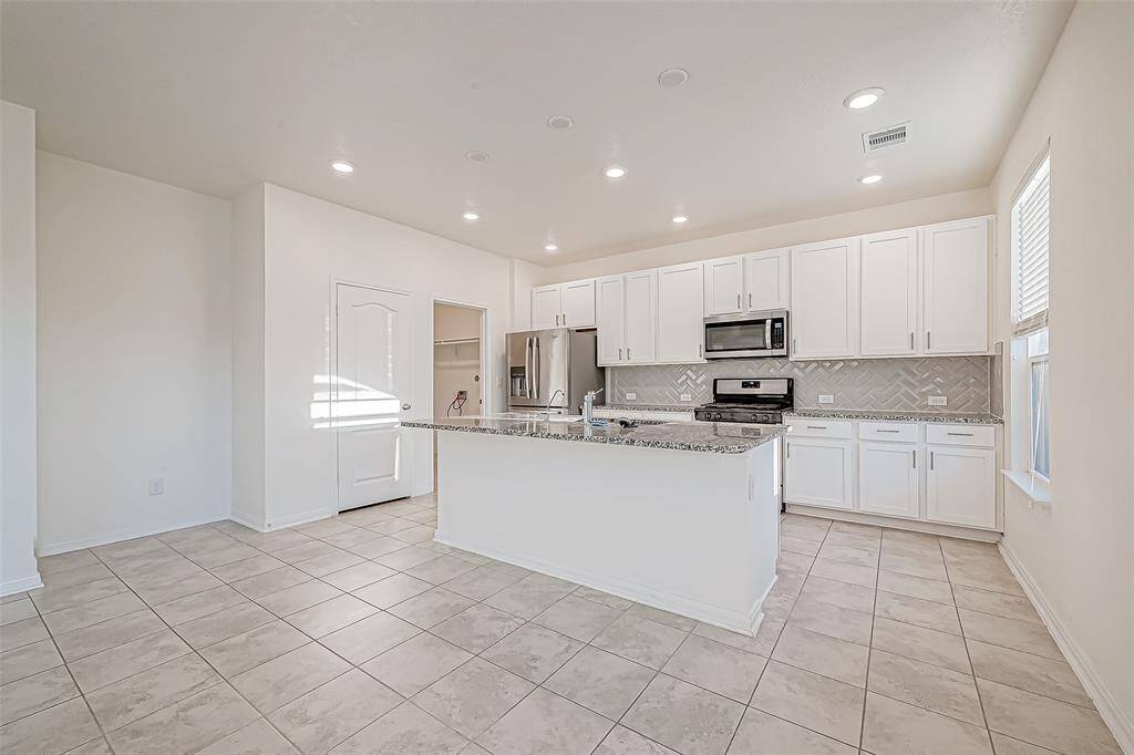 This immaculate kitchen is ready to keep up with your everyday hustle featuring crisp white cabinetry, granite counters, stylish herringbone backsplash, and sleek stainless steel appliances. The roomy pantry keeps the essentials in reach, while the island doubles as a prep station and the perfect perch for morning coffee or homework help.