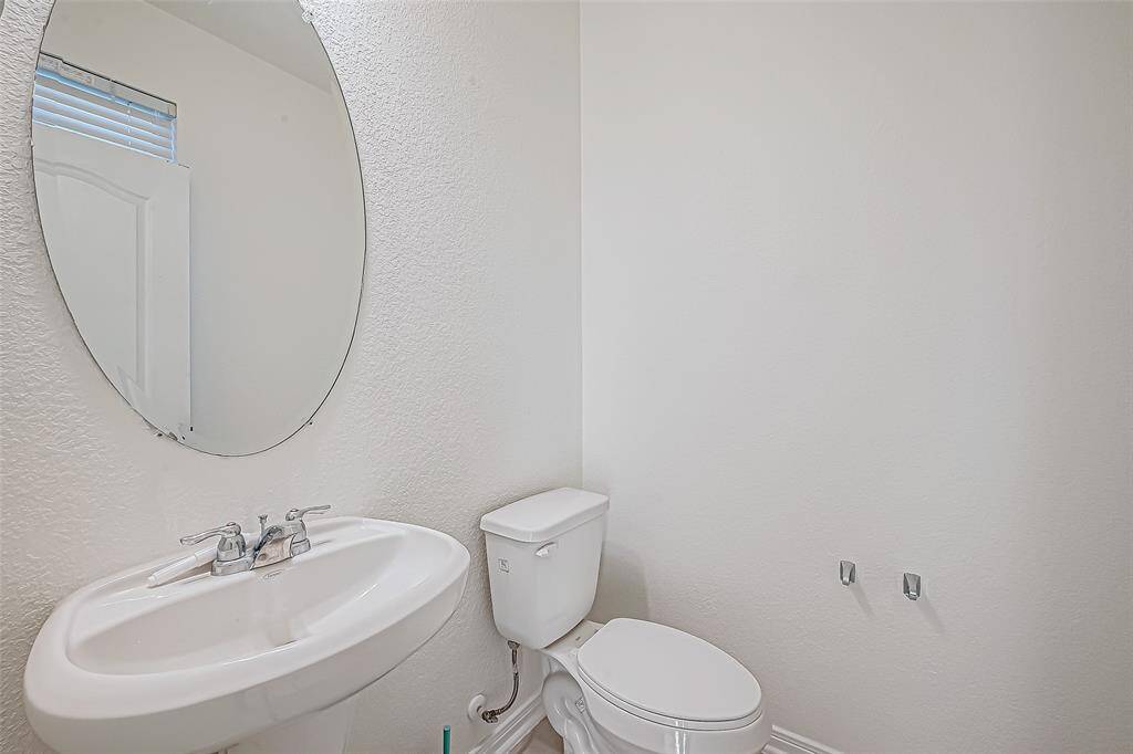 Conveniently located on the main floor, the powder bath features a classic pedestal sink and fresh, neutral finishes, perfect for guests and everyday use alike.