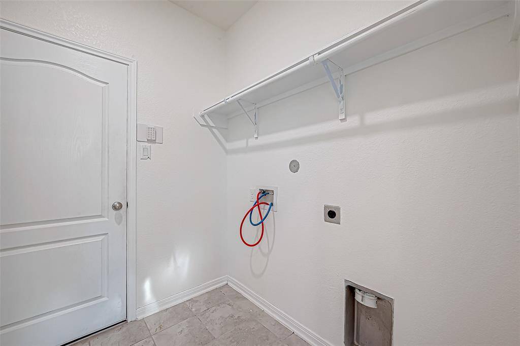 The first-floor utility room offers a smart and functional layout with built-in shelving for storage, a convenient hanging bar for clothes, and connections for both gas or electric dryers.