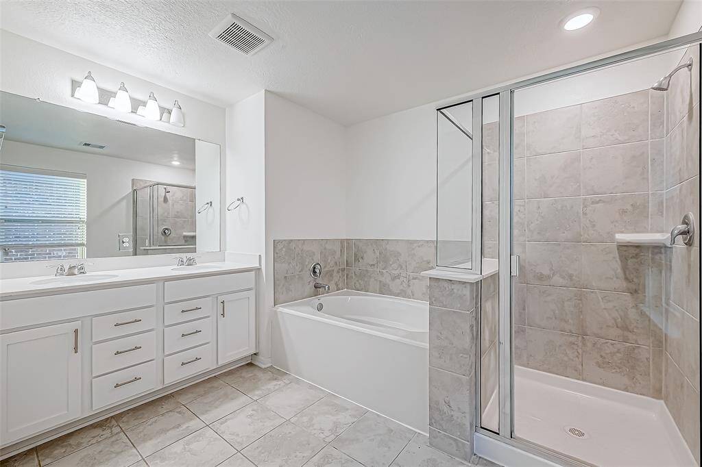 Enjoy a daily dose of luxury in this spa-inspired bathroom featuring a dual-sink vanity with ample storage, a relaxing soaking tub, and a spacious walk-in shower.