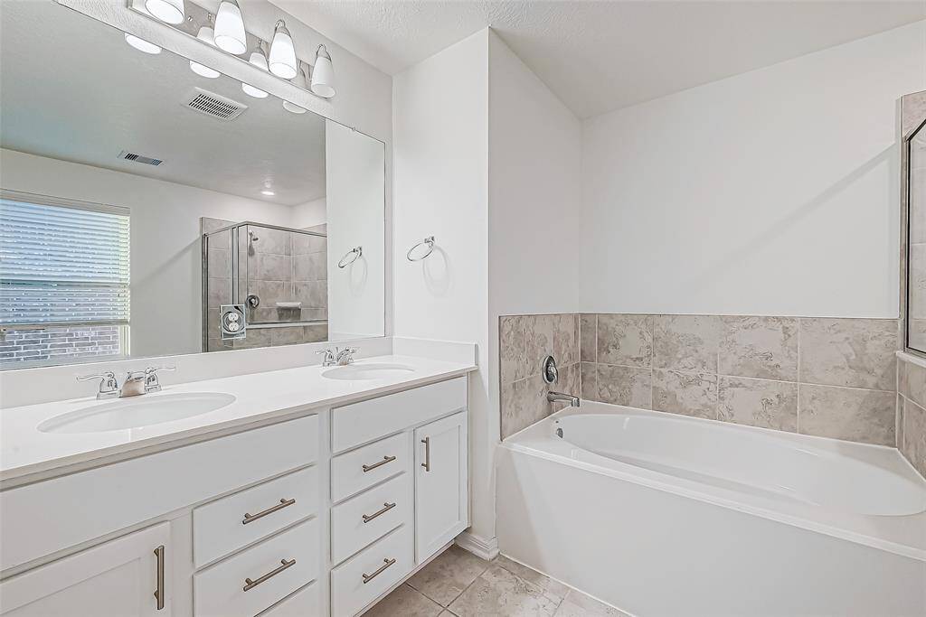 This bathroom’s spacious vanity offers plenty of storage to keep essentials organized, while the large mirror and bright vanity lights create a welcoming and functional space for your daily routine.