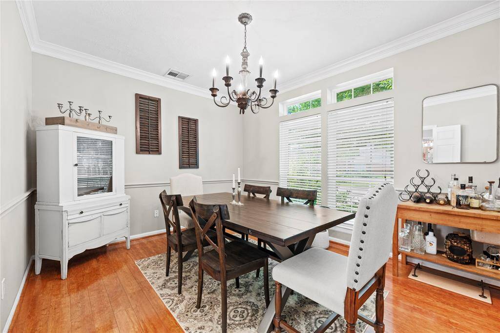 Just to the right of the entry, your formal dining room awaits—featuring elegant chair rail detailing, classic crown molding, a sparkling chandelier overhead, and a large, sun-filled window that bathes the space in natural light.