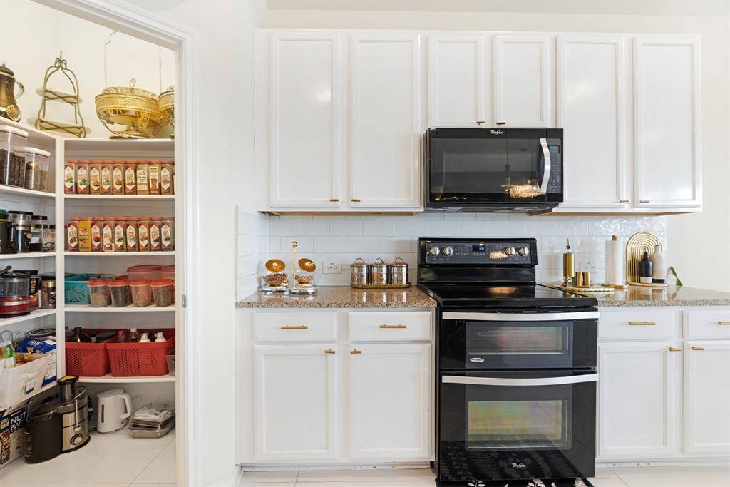 The kitchen also has black appliances and a walk-in pantry.