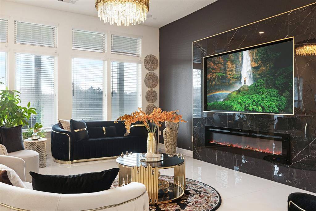 Living room features tile flooring, achandelier, high ceilings, cozy fireplace, accent wall, and a wallof windows.