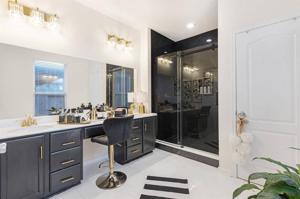 The primary bathroom features tile floors, dual sinks, dark cabinets, and walk-in shower with glass door.
