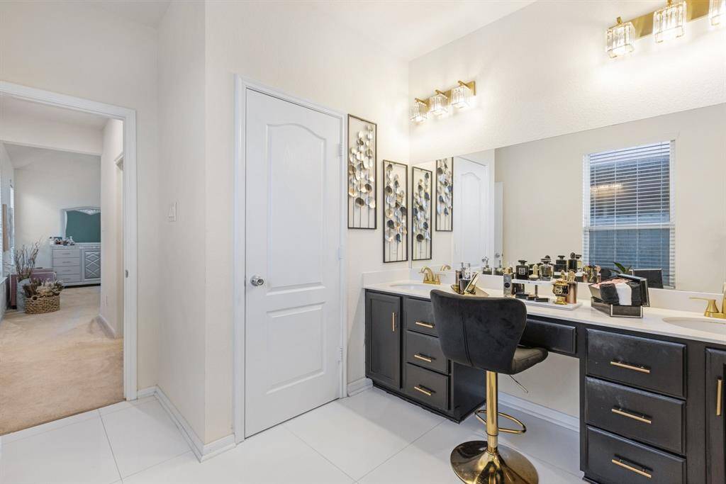 The primary bathroom features tile floors, dual sinks, dark cabinets, and walk-in shower with glass door.