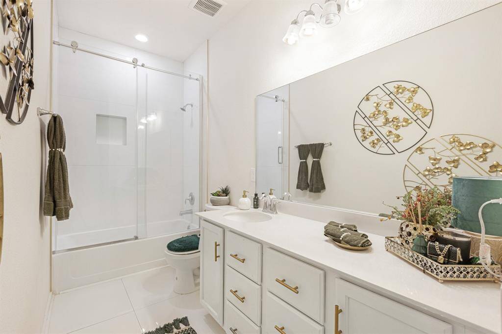 Secondary bathroom features atub/shower combo with glass door and long vanitywith plenty of counter space.