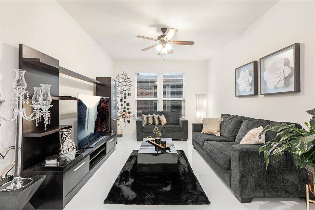 The formal dining room currently used as a den features tile floors, ceiling fan, and large windows.