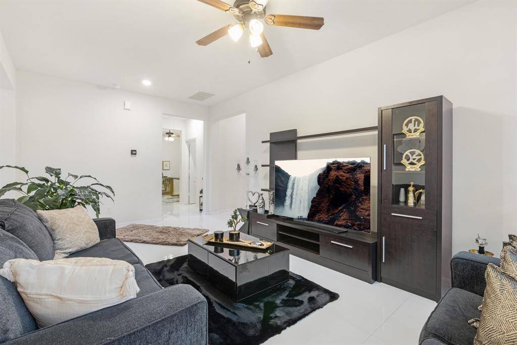 The formal dining room currently used as a den features tile floors, ceiling fan, and large windows.