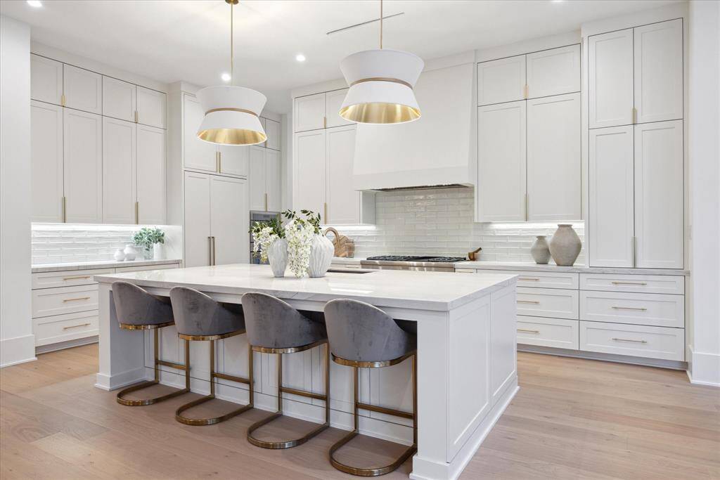 [KITCHEN] The chef’s kitchen is a masterpiece of French contemporary design, featuring top-of-the-line Thermador appliances seamlessly integrated with custom-framed cabinetry and a built-in refrigerator. Beautiful natural stone countertops complement the spacious, gracious island—perfect for meal prep and casual gatherings.