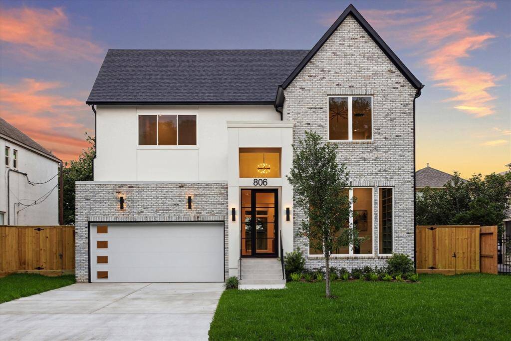 A modern glass front door sets a sleek tone, while beautiful, expansive windows glow warmly from within—offering a glimpse of the elegant interiors and creating a captivating street presence.