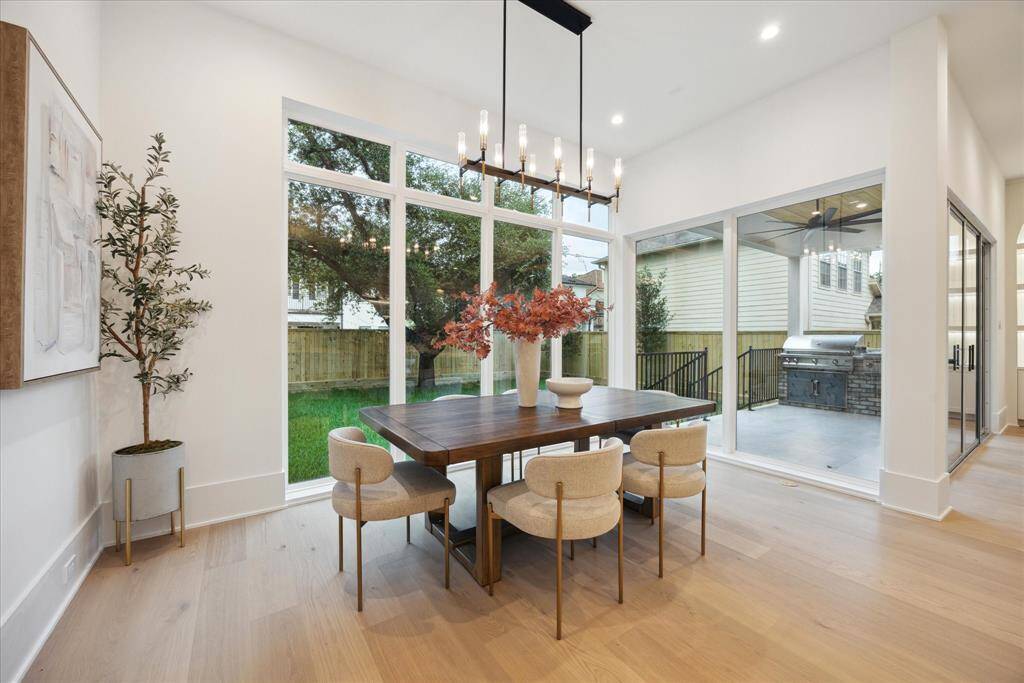 The charming breakfast area is illuminated by a stunning light fixture, creating a warm and inviting ambiance. Large windows look out onto the veranda, seamlessly blending indoor comfort with the beauty of outdoor living