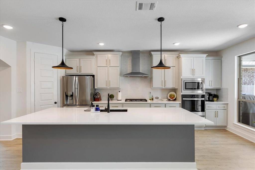 A expansive island offers ample room for entertaining, complemented by sleek stainless steel appliances that complete this stylish and modern culinary space.