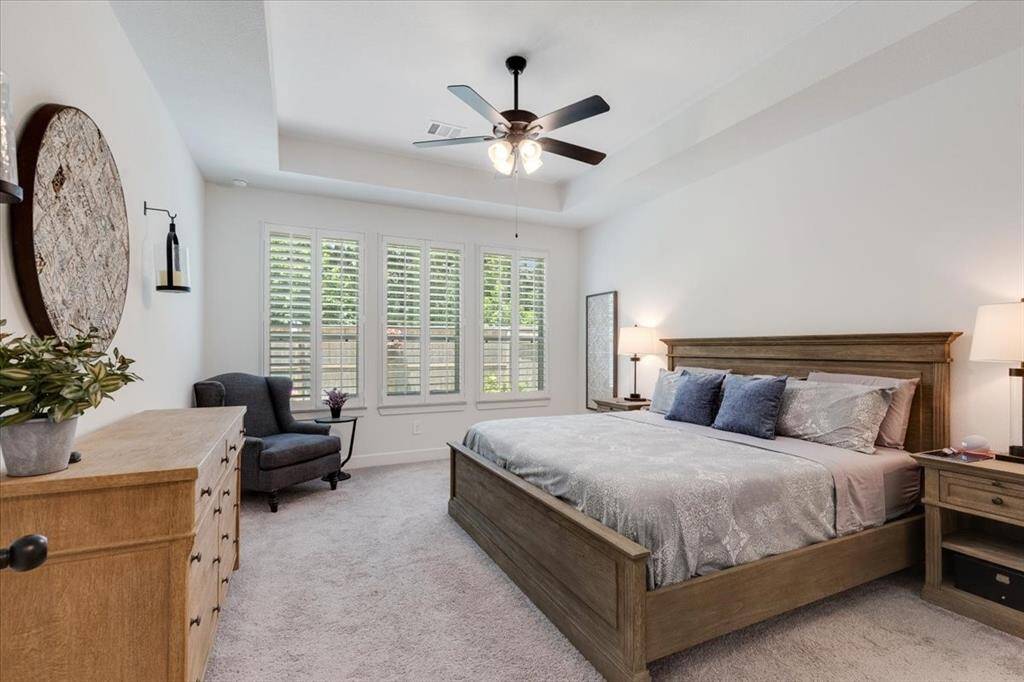 The primary retreat features plush carpeting and elegant plantation shutters for a cozy, refined feel.