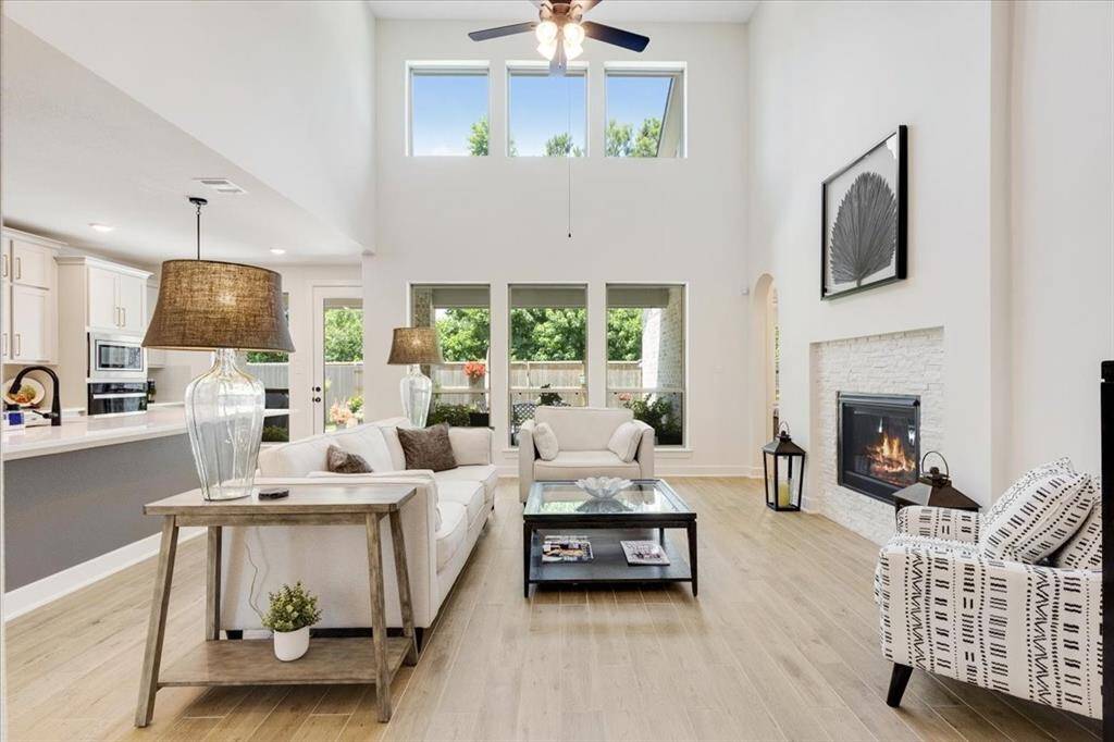 The family room flows seamlessly into the entertainment kitchen, featuring soaring ceilings and a cozy gas log fireplace—perfect for gathering and relaxing.