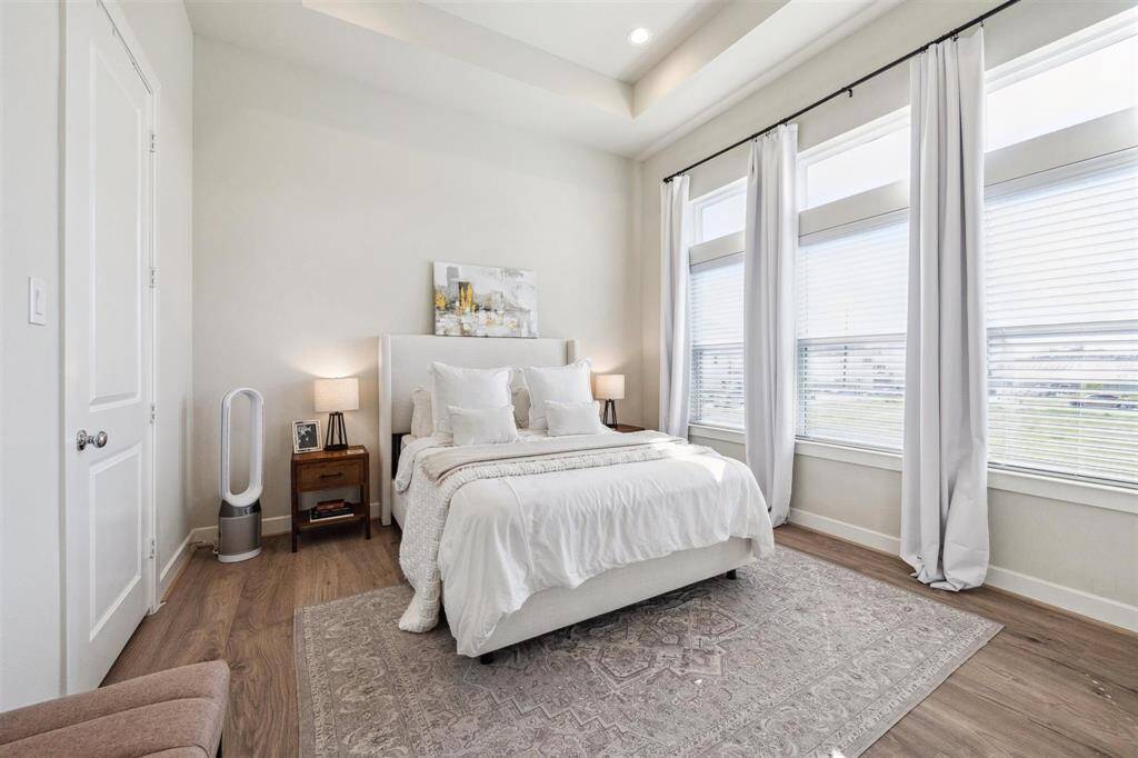 Master suite with coffered high ceiling, engineered flooring, walk in closet, and plenty of natural light.