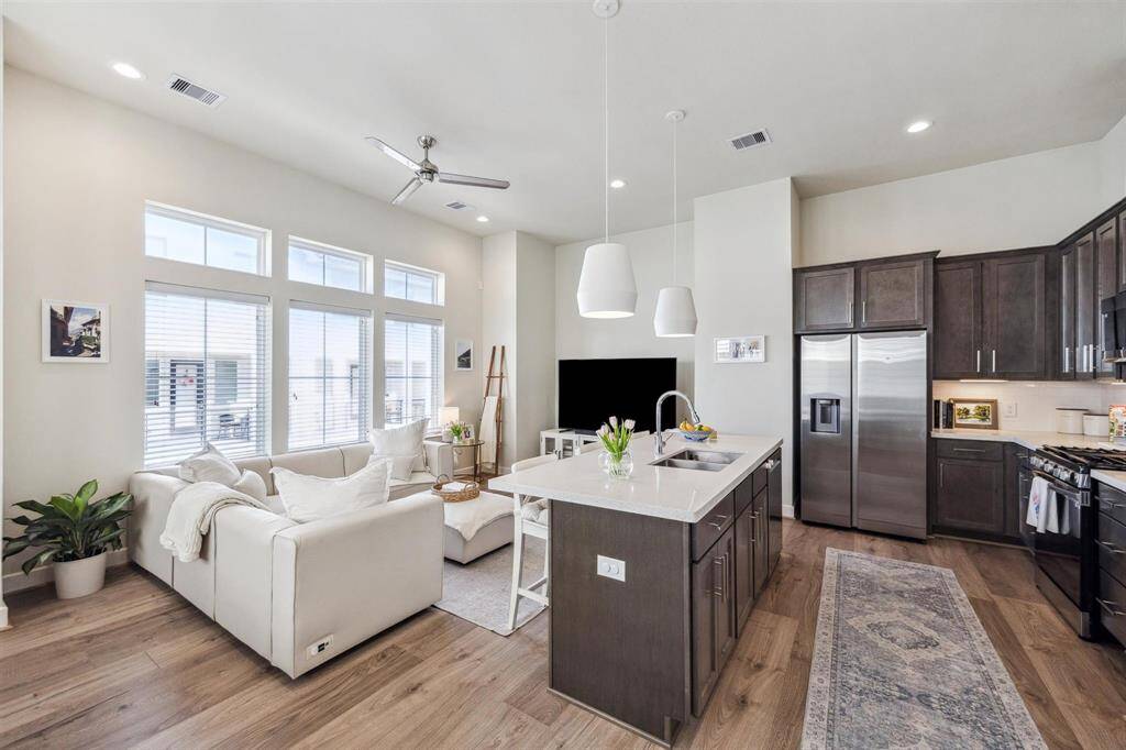 Living room and kitchen with breakfast bar, neutral colors, transitional light fixtures and more.
