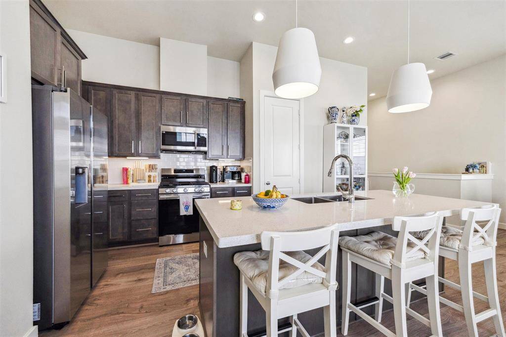 Another view of the kitchen with quartz countertops, stainless appliances and subway tiled backsplash.