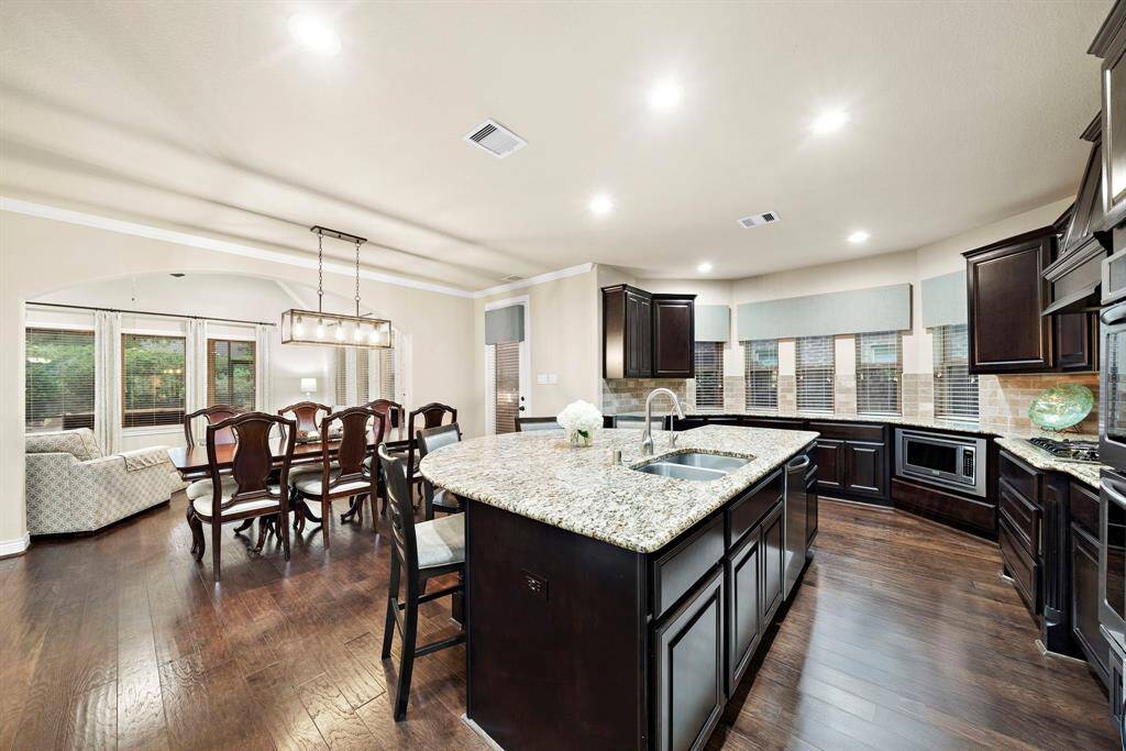 The kitchen anchors the main living space with expansive granite surfaces, hardwood flooring, and seamless access to both dining and relaxation areas—perfect for hosting with ease.