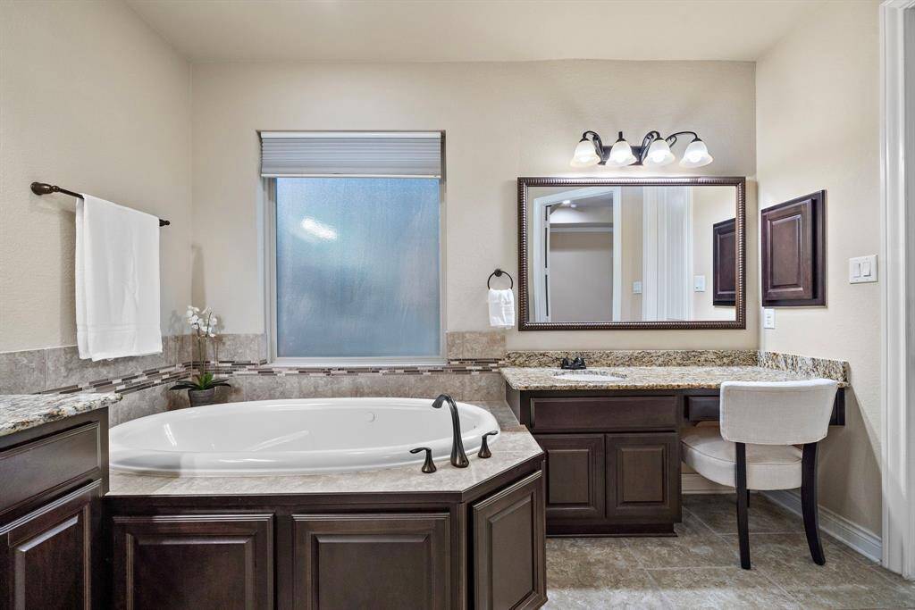 Granite counters wrap around the soaking tub and dedicated vanity space, combining style and function in a spa-inspired setting.