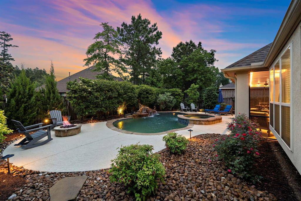 Framed by lush greenery, the saltwater pool and elevated spa create a resort-style retreat complete with a rock waterfall, cozy fire pit, and fully-equipped outdoor kitchen—ideal for effortless entertaining.