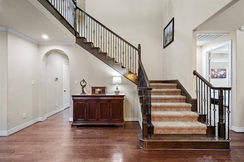 A wood-trimmed staircase with iron balusters offers a refined transition to the upper level, accented by detailed railwork and hardwood flooring below.