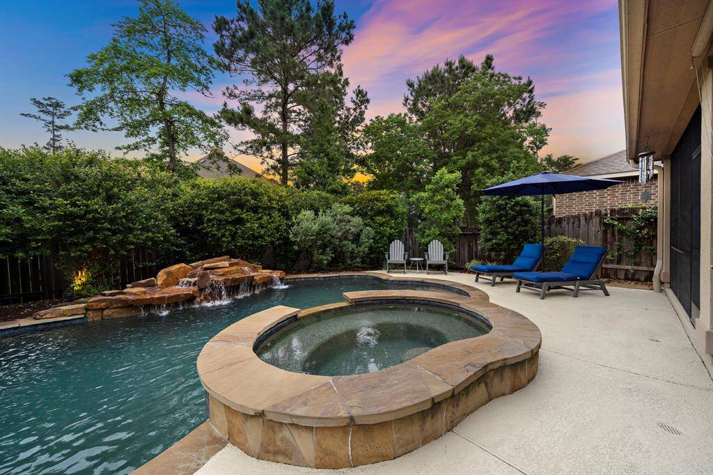 A multi-tiered waterfall spills into the curved saltwater pool, adding visual movement and a tranquil ambiance to the outdoor retreat.