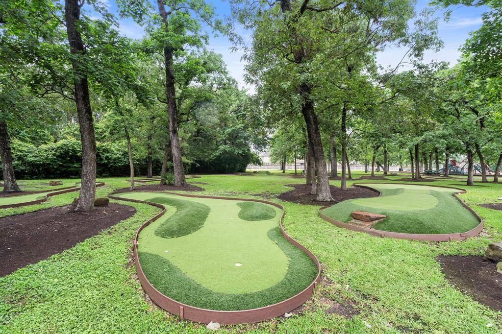 Challenge your short game on the community putting green surrounded by tall trees and lush landscaping. This unique outdoor feature adds recreational value to the neighborhood, offering residents a peaceful spot for relaxation and enjoyment.