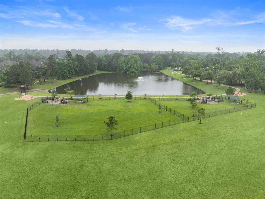 The neighborhood dog park features large, fully fenced play areas with separate shaded pavilions for resting and socializing. Scenic walking trails circle a peaceful lake with a central fountain, creating an inviting setting for outdoor recreation and relaxation.