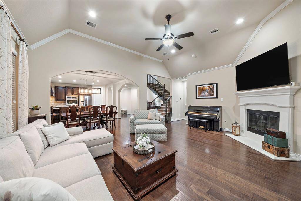 Wide-plank hardwood floors guide the open-concept layout toward the dining area and staircase, highlighting the thoughtful connectivity of the main level.