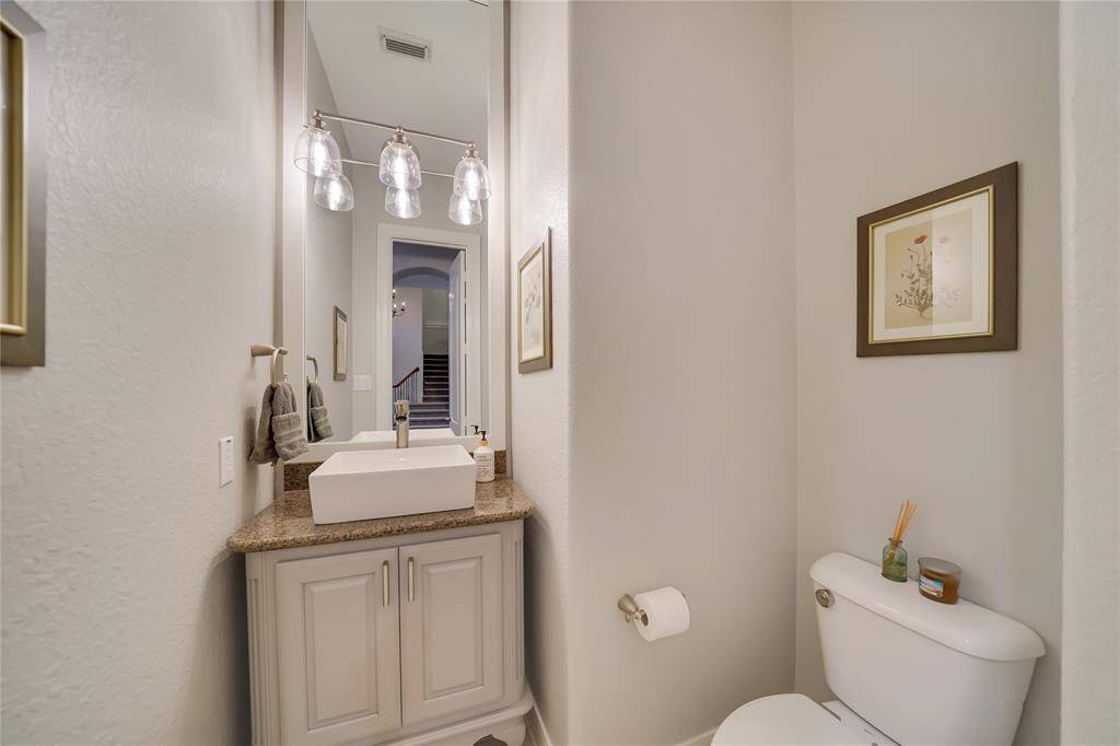 This is a compact, stylish half-bathroom featuring a modern vessel sink on a granite countertop, with elegant lighting and tasteful wall art, creating a cozy and functional space.