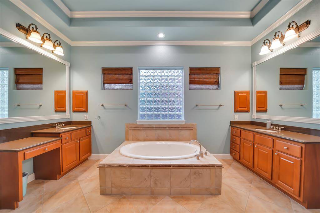 Oversized jetted tub & separate shower, dual sink vanity featuring silestone counters, framed mirrors
