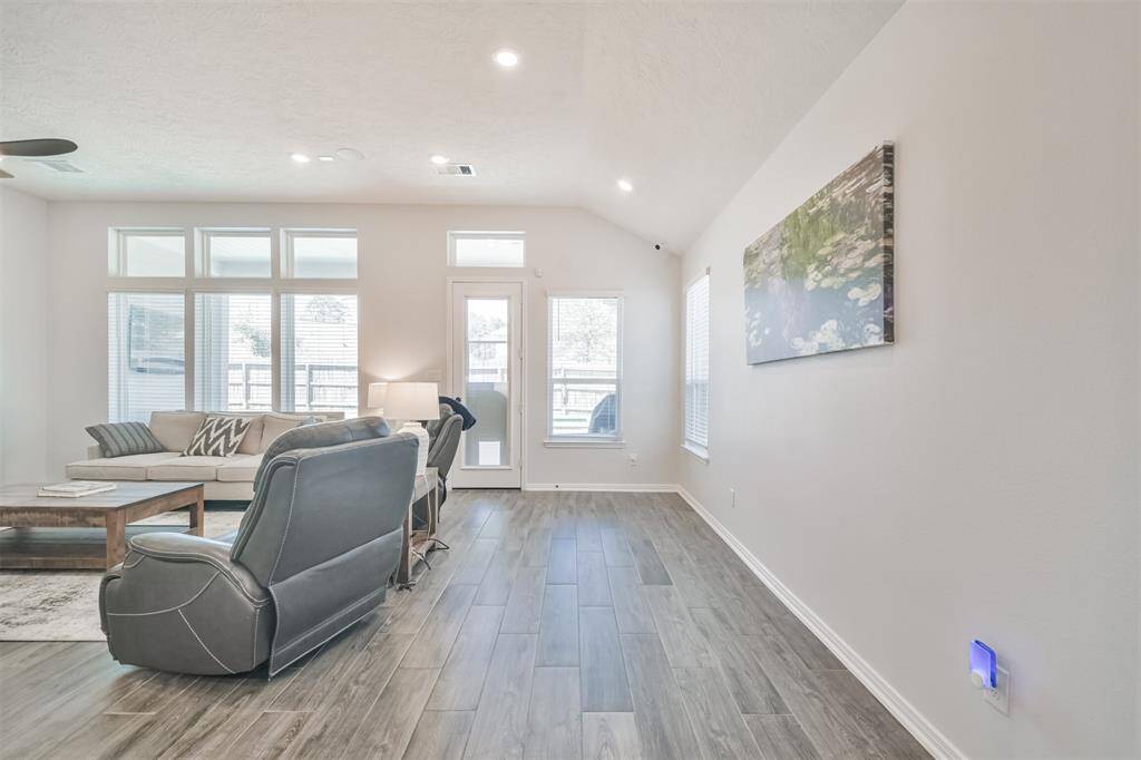 This photo showcases a bright, open living room with large windows, modern flooring, and neutral walls. The space features comfortable seating and tasteful decor, offering a welcoming and airy atmosphere.