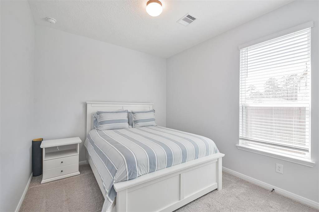 Thissize able primary bedroomis well-litt with natural light streaming through a large window, creating a bright and inviting atmosphere.