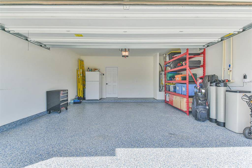 Spacious garage with a clean, speckled epoxy floor, ample shelving for storage, and essential utilities. Ideal for organization and vehicle parking.