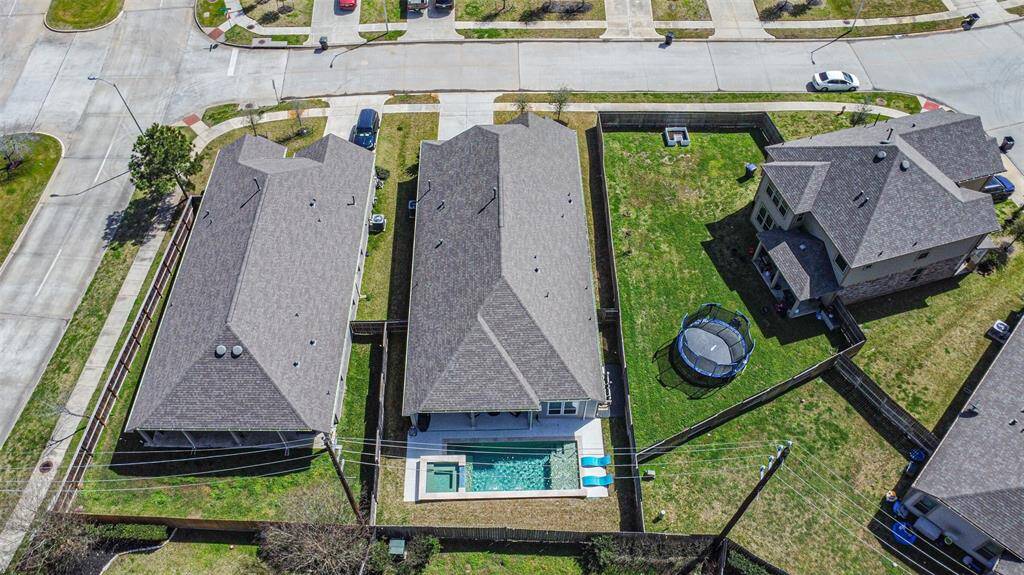 This aerial view showcases a suburban neighborhood with a central house featuring a backyard pool.